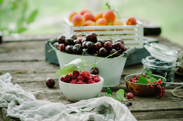 Mix of fresh berries and fruit in vintage wooden box on rustic wooden background. Raw healthy food. Assorted summer berries and fruit.
