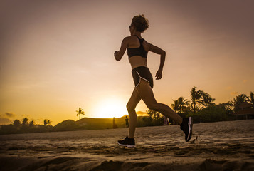 young attractive and fit runner woman with athletic body running on beautiful Summer sunset light training jogging workout outdoors at tropical beach in fitness concept