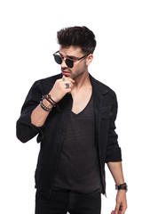 pensive young man in black clothes looks to side