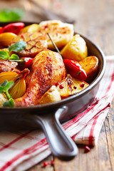 Oven-baked chicken with vegetables and fresh herbs. Homemade food. Symbolic image. Concept for a tasty and hearty dish. Rustic wooden background. 