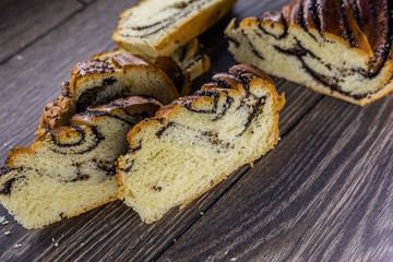 Roll with poppy seeds sliced lying on the table. Bread products.