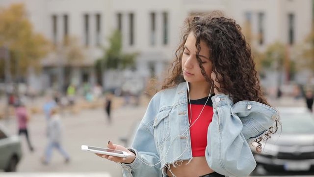 Portrait of young multiracial girl puts on earphones in urban city square