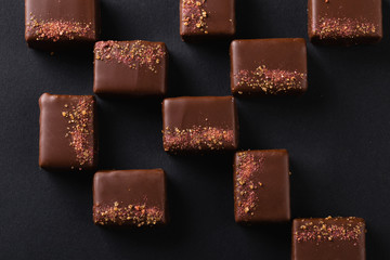 Luxury handmade bonbons decorated with pink salt on black background