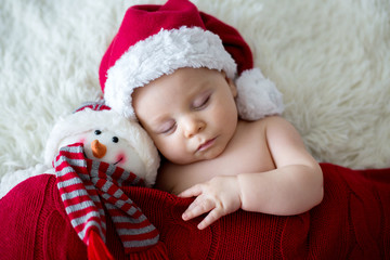 Little sleeping newborn baby boy, wearing Santa hat