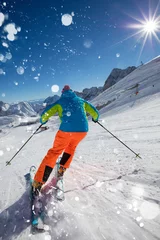 Gordijnen Skier skiing downhill in high mountains © Lukas Gojda