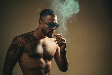Tattooed man with cigar. Cigar smoking enjoy life and moment. Portrait of a bearded businessman...
