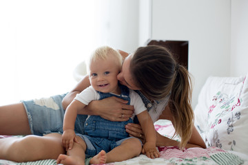 Mom and toddler baby boy, enjoying a nice afternoon rest in a sunny bedroom