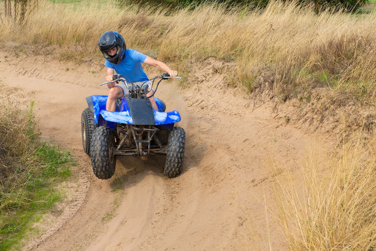 Young man driving quad through curve
