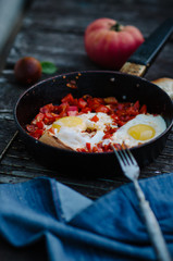 Shakshuka, Fried Eggs with Tomato Sauce in a Pan, Rustic Style and Wooden Background