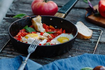 Shakshuka, Fried Eggs with Tomato Sauce in a Pan, Rustic Style and Wooden Background
