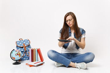 Young concentrated smart woman student holding using calculator solving math equations sitting near globe, backpack, school books isolated on white background. Education in school university college.