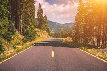 Naklejka premium Mountain road. Landscape with rocks, sunny sky with clouds and beautiful asphalt road in the evening in summer. Vintage toning. Travel background. Highway in mountains. Transportation