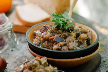 Traditional Caucasian saute from stewed eggplants, peppers, onions, tomatoes and herbs on the old background in rustic style