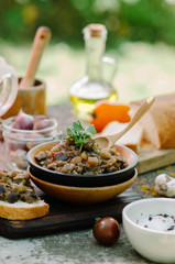 Traditional Caucasian saute from stewed eggplants, peppers, onions, tomatoes and herbs on the old background in rustic style