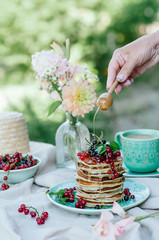 Stack of banana pancakes on a blue plate with fresh berries and honey for breakfast
