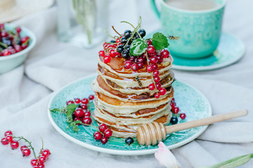 Stack of banana pancakes on a blue plate with fresh berries and honey for breakfast