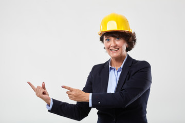 Mature engineer lady in hard hat indicating