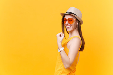 Portrait of smiling excited young woman in straw summer hat, orange glasses doing winner gesture, saying Yes isolated on yellow background. People sincere emotions lifestyle concept. Advertising area.