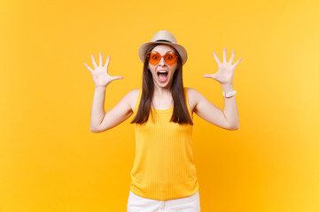 Portrait of excited screaming young woman in orange glasses spreading hands, keeping mouth wide...