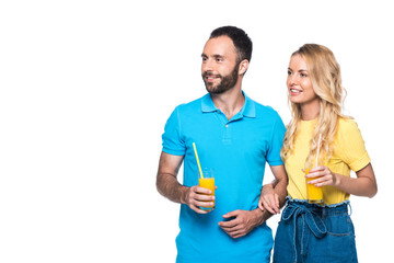 Fototapeta premium couple holding glasses with orange juice and looking away isolated on white