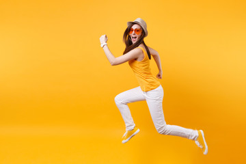 Fototapeta na wymiar Portrait of excited smiling young jumping high woman in straw summer hat, orange glasses copy space isolated on yellow background. People sincere emotions, passion lifestyle concept. Advertising area.
