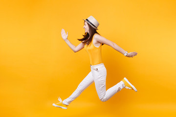 Portrait of excited smiling young happy jumping high woman in straw summer hat, copy space isolated on yellow orange background. People sincere emotions, passion lifestyle concept. Advertising area.