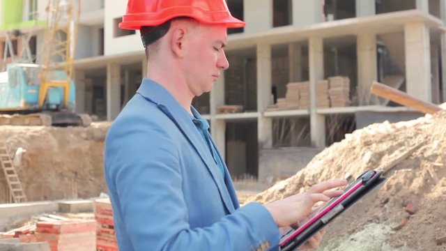 young architect working on a tablet near the construction site
