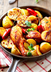 Oven-baked chicken with vegetables and fresh herbs. Homemade food. Symbolic image. Concept for a tasty and hearty dish. Rustic wooden background.