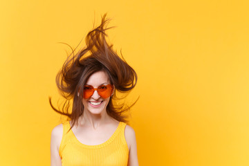 Portrait of excited cheerful laughter funny comic woman in orange glasses with fluttering hair copy space isolated on yellow background. People sincere emotions, lifestyle concept. Advertising area.