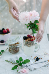 Woman's hands as she eats healthy breakfast .Yogurt with strawberries and granola in a bowl on the table.