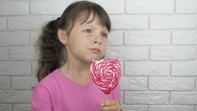 Child with ollipop. Little girl with a big candy.
