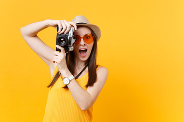 Tourist woman in summer casual clothes, hat take picture on retro vintage photo camera isolated on yellow background. Girl traveling abroad to travel on weekends getaway. Air flight journey concept.
