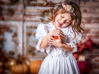 Little girl in vintage dress. Little girl is holding pumpkin. Beautiful little girl in white dress © alatielin