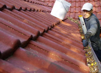 The man cleans the gutters on the roof © Skórzewiak