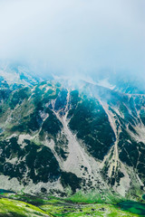 Beautiful foggy alpine high mountains peaks, blue sky background. Amazing Mountain hiking paradise...