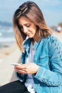 Pretty young woman reading a mobile phone message