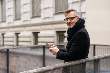 Businessman in overcoat standing on a bridge