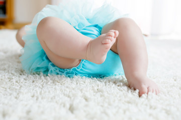 Closeup of legs and feet of baby girl on white background wearing turquoise tutu skirt. © Irina Schmidt