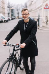 Mature man standing with bicycle in street
