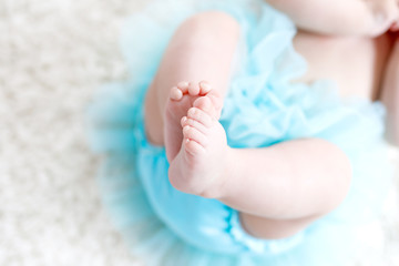 Close-up of legs and feet of baby girl on white background wearing turquoise tutu skirt. © Irina Schmidt