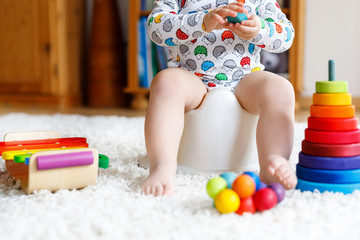 Closeup of cute little 12 months old toddler baby girl child sitting on potty.