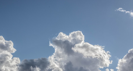 Clouds illuminated by the sun on a bright blue background