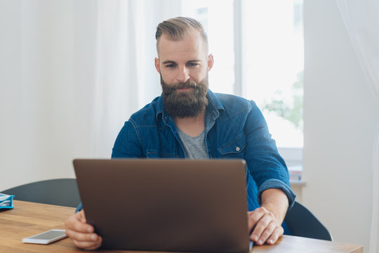 Bearded casual man working on a laptop at home