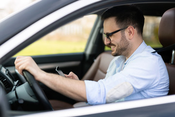 Businessman ignoring safety and texting onmobile phone while driving