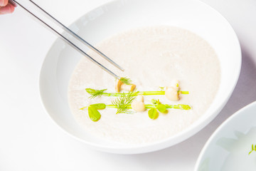 Cook chef making creme soup with herbs and mushrooms.
