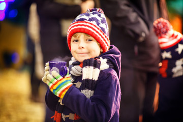 Little kid boy drinking hot chocolate on Christmas market