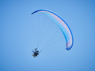 Powered paraglide or paramotor against blue sky. Paragliding
