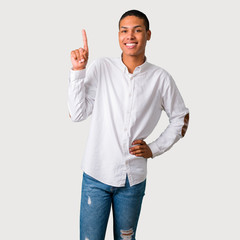 Young african american man showing and lifting a finger in sign of the best on grey background