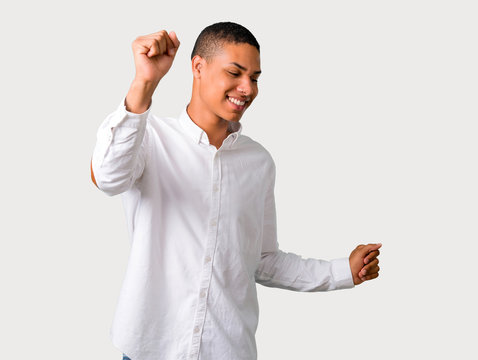 Young african american man enjoy dancing while listening to music at a party on grey background