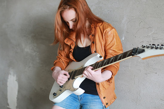 Young red-haired girl with an electric guitar. Rock musician gir